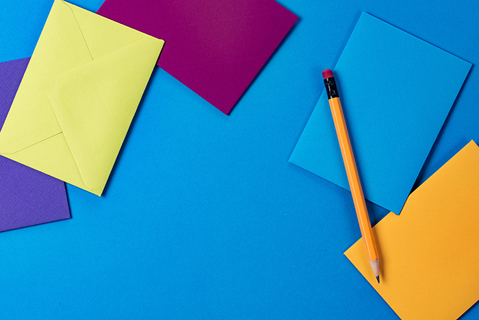 Colourful paper, envelopes and a pencil laid out for a design session